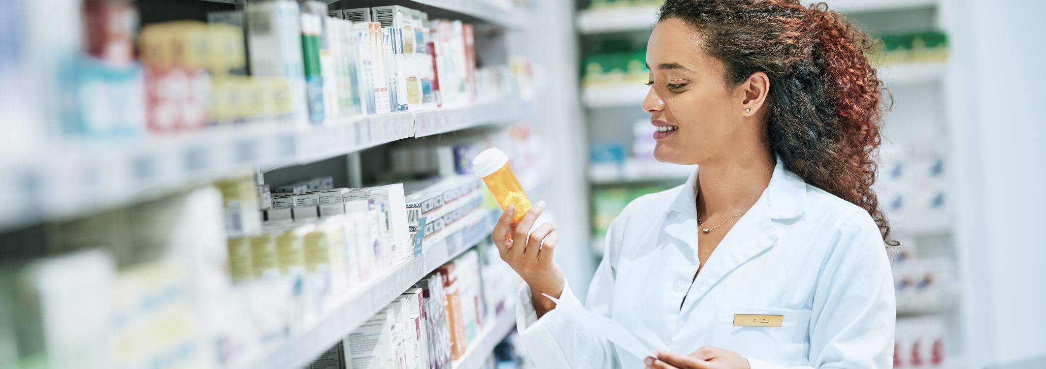 A pharmacist reviews a prescription in front of shelves of medicine